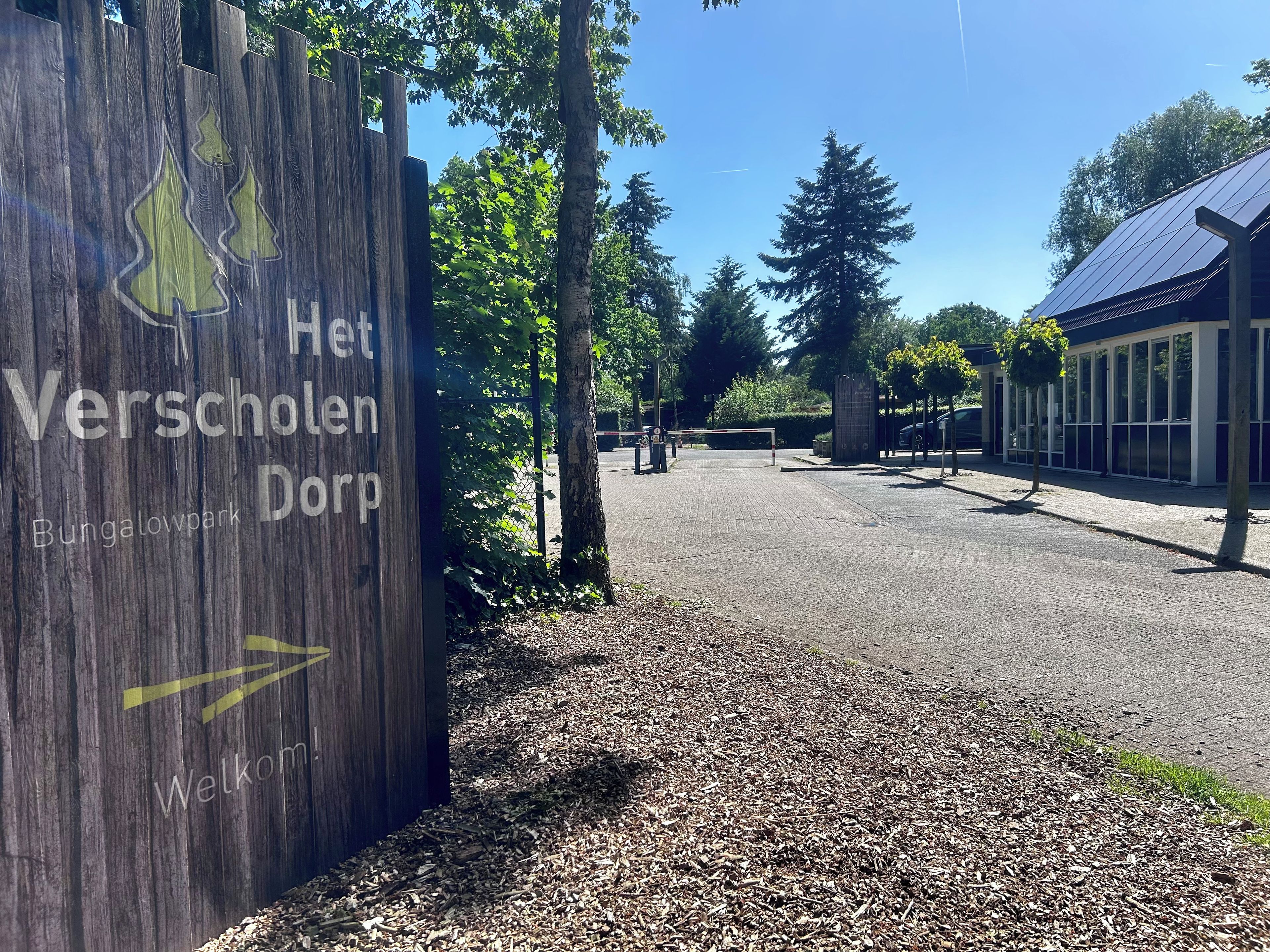 Un panneau en bois indiquant « Het Verscholen Dorf » et « Bungalowpark », signalant la présence d’un parc.