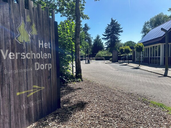A wooden sign with 'Het Verscholen Dorf' and 'Bungalowpark' indicating a park area.