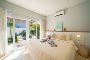 Ein Schlafzimmer mit einem großen Bett, Blick ins Freie und einem Deckenventilator.