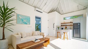 Uma sala de estar moderna com um sofá, mesa de centro e uma grande planta em vaso.