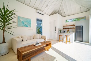 Ein modernes Wohnzimmer mit einer Couch, einem Couchtisch und einer großen Topfpflanze.