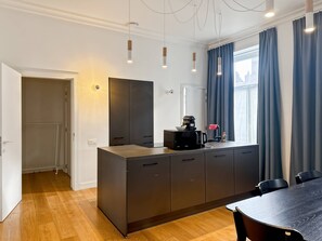 Eine moderne Küche mit integriertem Mikrowellenherd, einer Kaffeemaschine und einem fenster mit Vorhängen.