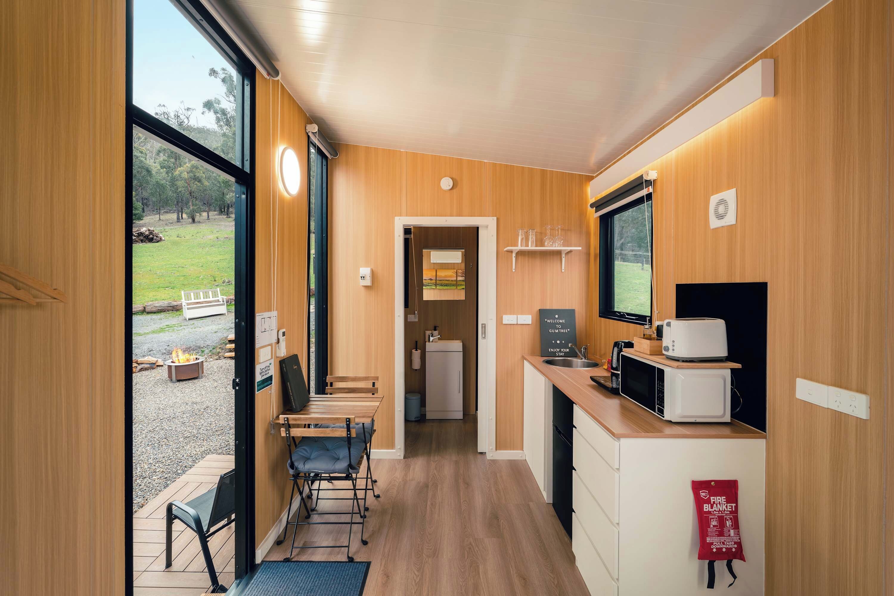 A compact kitchen with a dining area, a fire blanket, and a view of the outdoors.