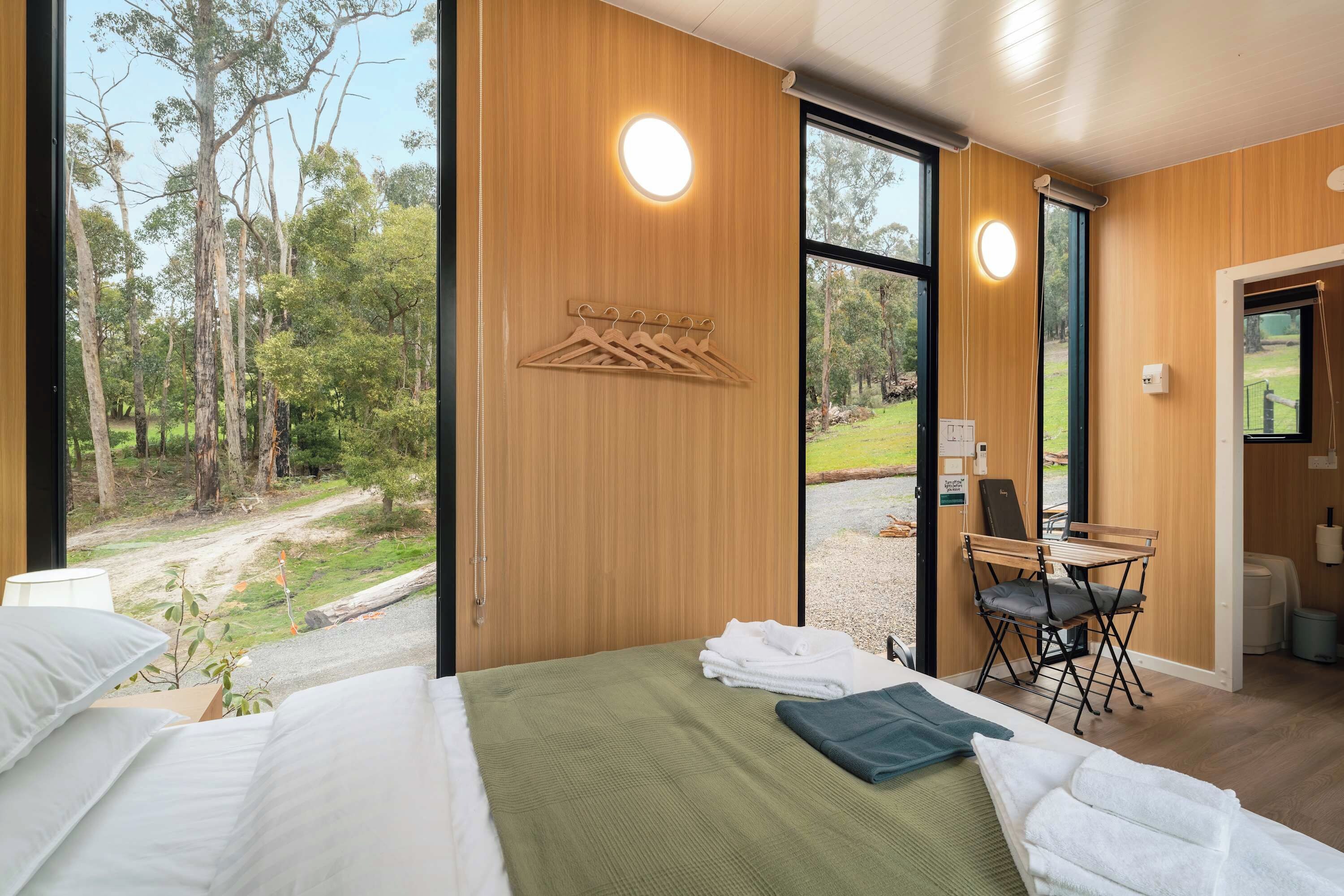 A bedroom with a bed, a desk, and a view of the outdoors.