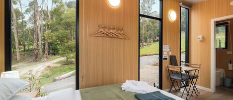 A bedroom with a bed, a desk, and a view of the outdoors.