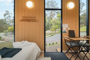Una habitación con cama, un escritorio con silla y vistas al exterior.