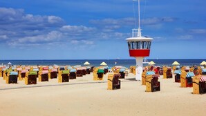 En strand med rækker af strandstole og et redder-tårn.