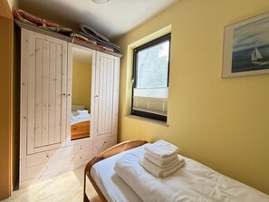 Ein Schlafzimmer mit Bett, Kleiderschrank, Fenster und einem Bild an der Wand.