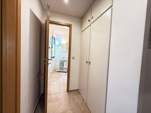 A narrow hallway with a wooden door leading to a bathroom with a white sink and a small white cabinet. - Hafenliebe Travemünde - "Hafenliebe" Vacation Rental – A Beachfront Vacation in (Lübeck)