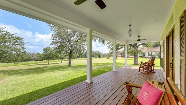 A covered porch with wooden flooring, a rocking chair, and a bench. - On 174 Acres! Ranch House in Colorado County (Weimar)
