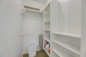 Une buanderie blanche avec des étagères, un panier et un porte-serviettes.