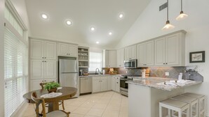 A kitchen with white cabinets, a central island, a dining table with chairs, and pendant lighting. - On 174 Acres! Ranch House in Colorado County (Weimar)