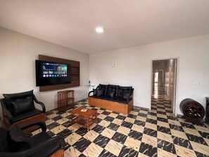 A living room with a television, a sofa, a coffee table, and a patterned floor. - Cozy house in the center of Rio das Ostras, 150 meters from the beach. (Rio das Ostras)