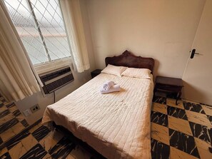 Ein Hotelzimmer mit einem Bett, einem Vorhangfenster, einem Heizkörper und einem Schachbrettfußboden.