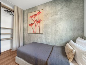 Une chambre à coucher comprenant un lit, une œuvre d’art accrochée au mur, une armoire et un porte-manteau mural.