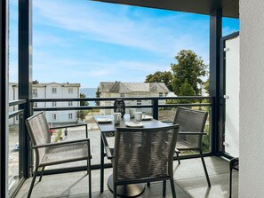 A balcony with a table and chairs, overlooking a residential area with houses and a clear sky. - NEW Freiraum Fünf - FREIRAUM FÜNF - Stylish, High-Quality Living (Sassnitz)