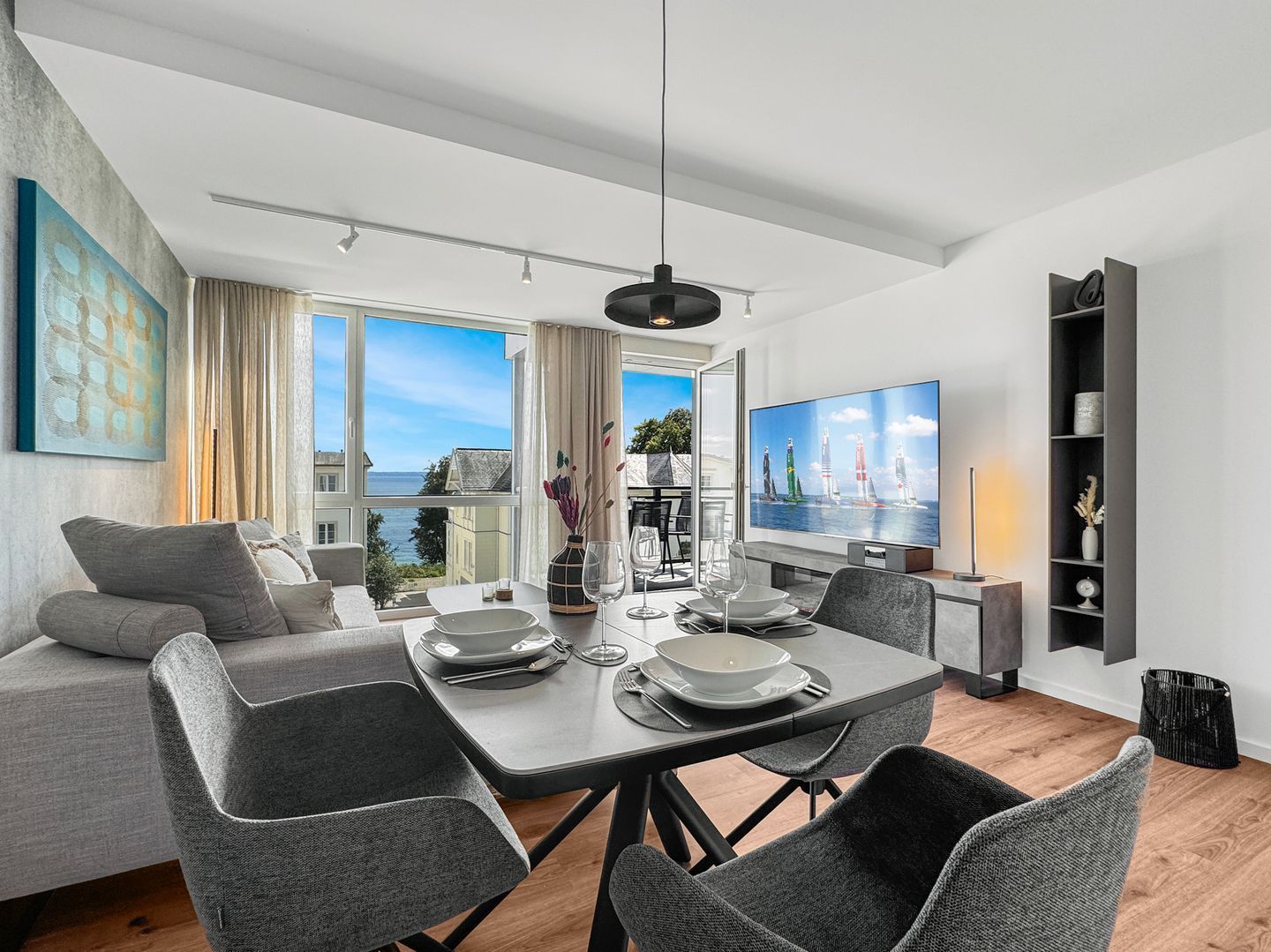 Una sala de estar moderna con comedor, ventanas amplias y un televisor de pantalla plana.