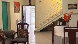 A living room with a sofa, chairs, a dining table, a staircase, and a ceiling fan. - A beautiful, comfortable, and safe home for the whole family (Santo Domingo Este)