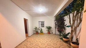 A hallway with patterned flooring, potted plants, and a window. - A beautiful, comfortable, and safe home for the whole family (Santo Domingo Este)