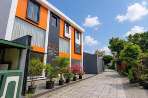 Ein modernes Gebäude mit einem Schild für 'House of ALFITA', das Dienstleistungen wie Gastaufnahme, Betreuung durch einen Professor und Verpflegung anbietet.