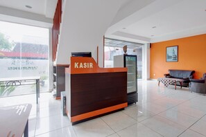 A reception desk with 'KASIR' signage, a glass display case, and a seating area with a checkered tablecloth. - House of Alfita • Deluxe Retreat (Yogyakarta)