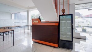 Una reception con una vetrina, una scalinata e un'area salotto con tavoli e sedie.