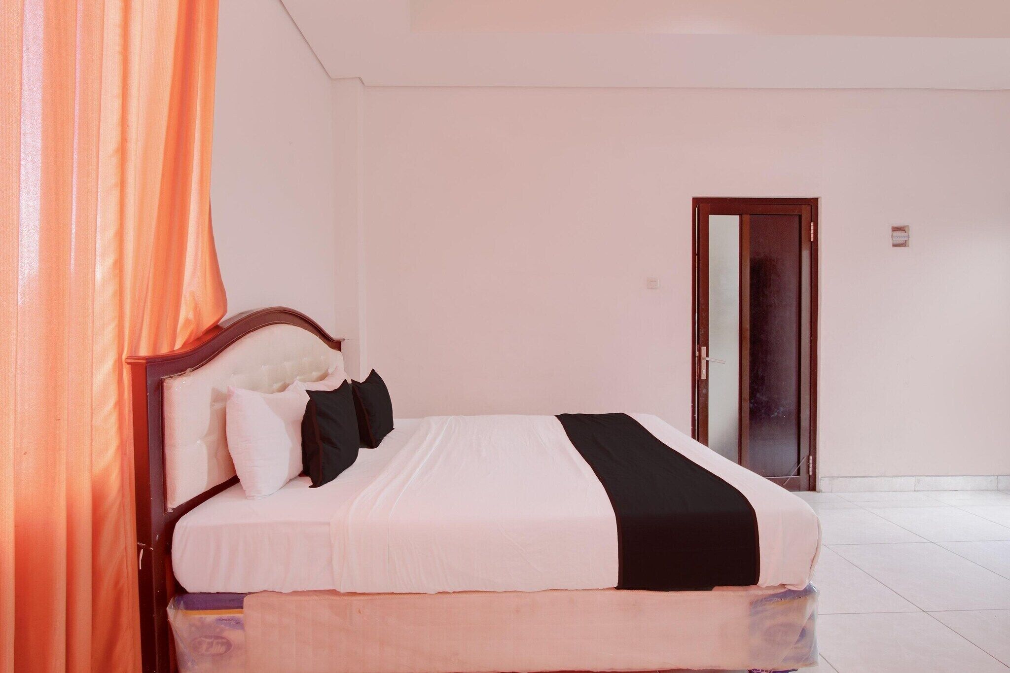 A bedroom with a bed, pillows, a nightstand, and a door.