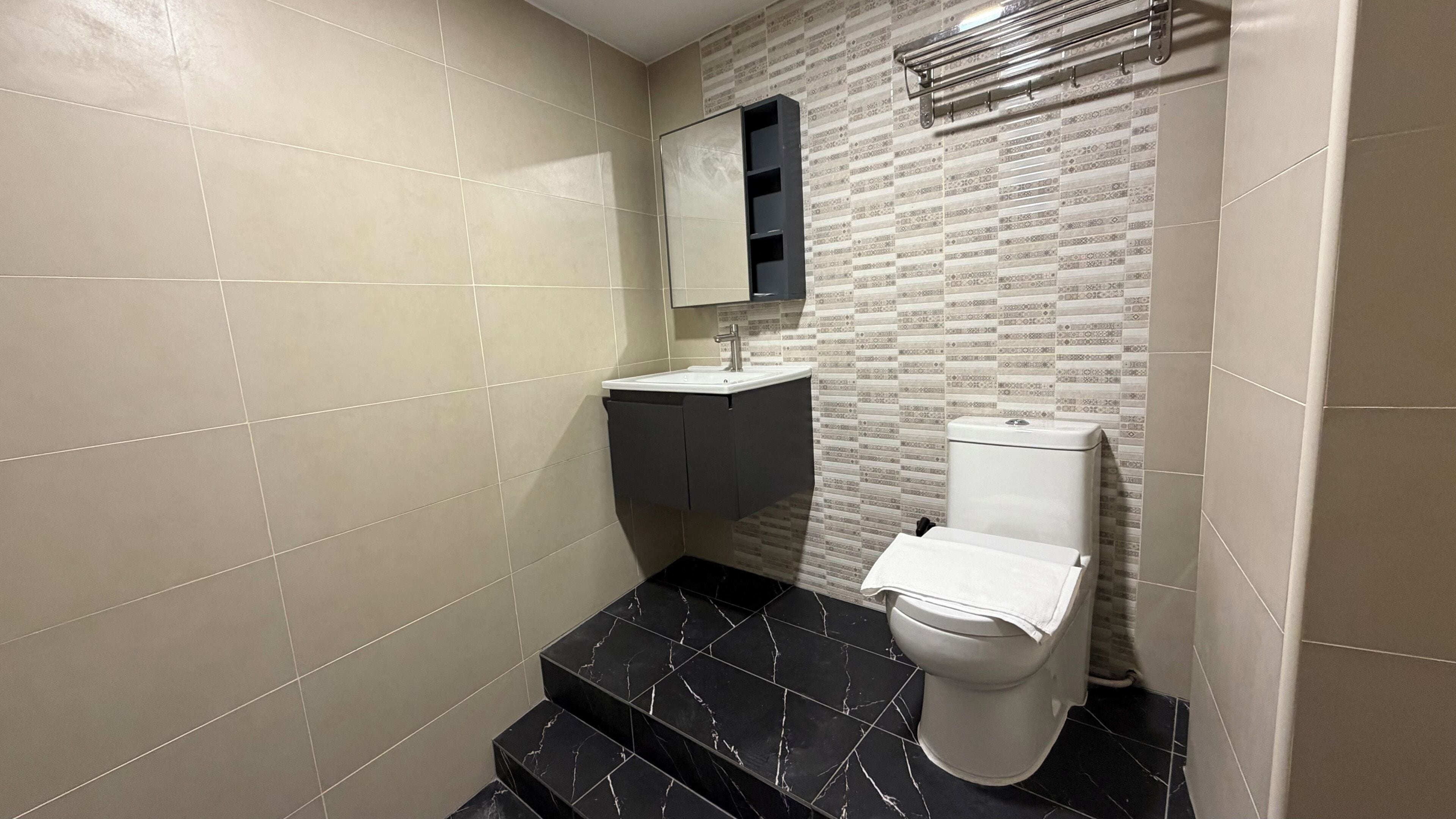 Un baño con inodoro, lavamanos y espejo.