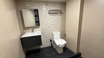 Un baño con lavamanos blanco, un espejo, un inodoro y un perchero para toallas.