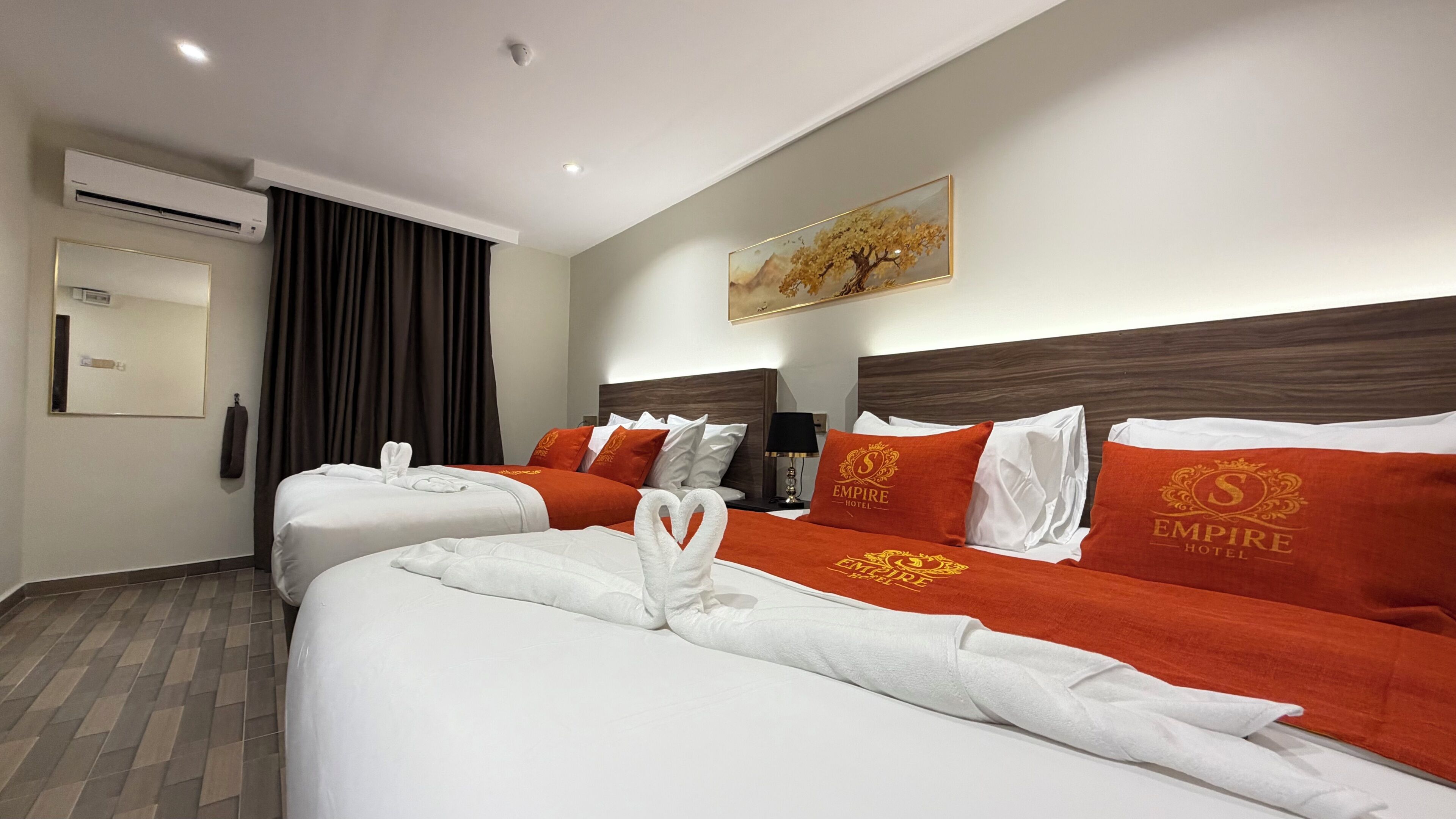 A hotel room with two beds, a large painting, an air conditioning unit, and a telephone.