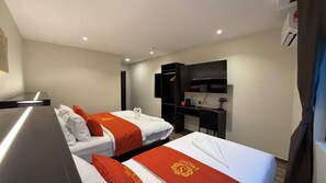 Habitación de hotel con dos camas, un escritorio, un armario y un televisor de pantalla plana.