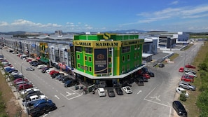 A multi-story hotel with a prominent green and yellow facade, multiple parking spaces, and a clear view of the surrounding area.