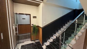 Un moderno vestíbulo de hotel con una escalera, un mostrador de recepción y un letrero que indica el primer piso.