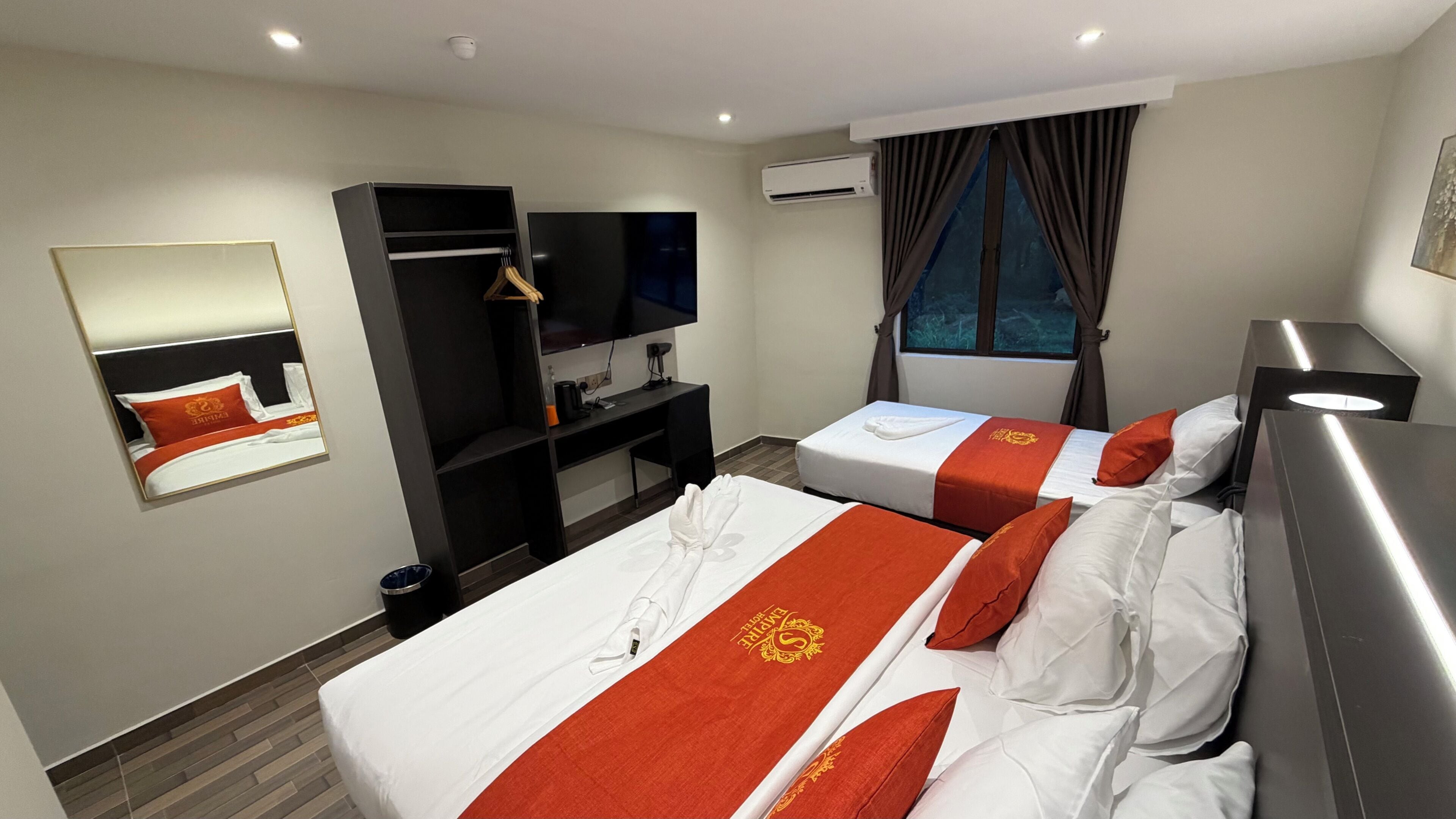 A hotel room with two beds, a TV, a desk, and a wardrobe.