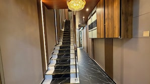 A modern hotel reception area with a marble staircase leading to the upper floors.