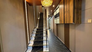A modern hotel reception area with a marble staircase leading to the upper floors.