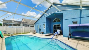 A swimming pool with a clear blue water, surrounded by a covered area with a blue wall and a roof structure. - Pool, Hot Tub & Kids' Play Area! Davenport Home (Davenport)
