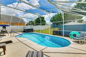 A covered outdoor swimming pool with a hot tub, lounge chairs, and a slide. - Pool, Hot Tub & Kids' Play Area! Davenport Home (Davenport)
