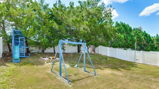 A backyard with a swing set, a slide, and a fenced area. - Pool, Hot Tub & Kids' Play Area! Davenport Home (Davenport)