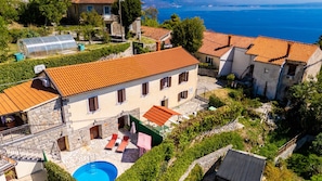Una villa con piscina, techo de tejas de arcilla y vista al mar.