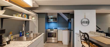 Uma cozinha moderna com eletrodomésticos de aço inoxidável, forno embutido e micro-ondas.