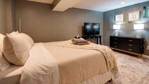 Un dormitorio de hotel con cama, televisor, cómoda y lámparas de pared.