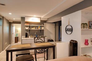 Eine kleine Küche mit Essbereich, einer Kaffeemaschine und einem an der Wand befestigten Schild.