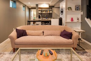 A living room with a beige sofa, a glass coffee table, and a kitchen in the background. - Remote Work Haven! Studio 8 Mi to Lincoln Memorial (Washington)