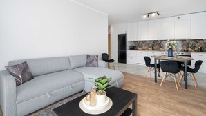 Un saló modern amb un sofà gris, una taula de centre i una zona de dinar amb una taula rodona i cadires.