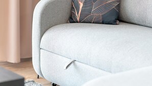 Un saló modern amb un sofà gris, un coixí estampat, una làmpada de peu negra i una cortina.