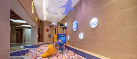 A children's play area with a slide, ball pit, and colorful wall decorations.
