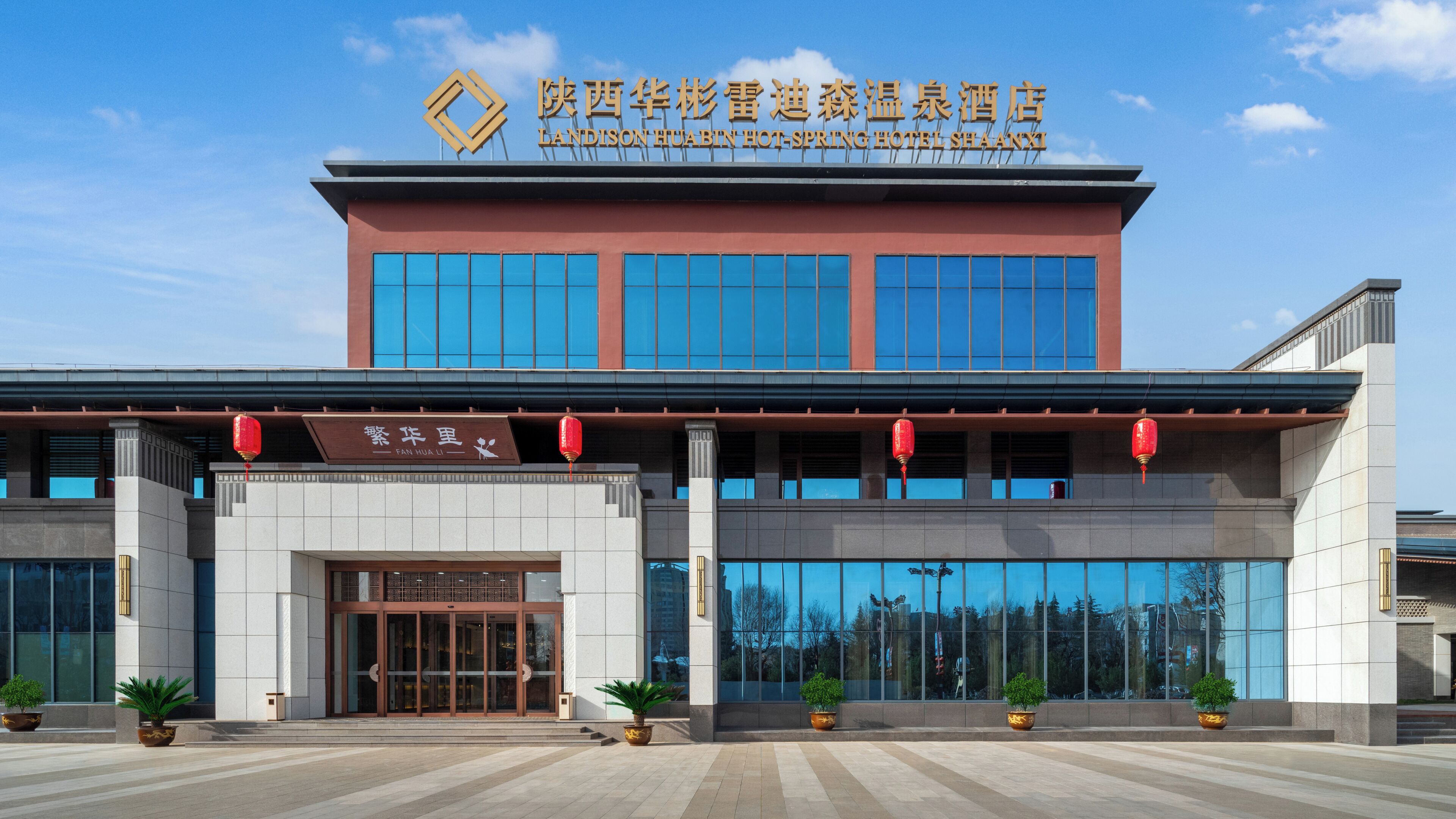 Ein Hotel mit moderner Fassade, großen Fenstern und einer Beschilderung in Chinesisch und Englisch.
