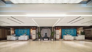 A modern hotel lobby with marble reception desks, a central decorative wall, and a high ceiling with recessed lighting. - LANDISON HUABIN HOT-SPRING HOTEL SHAANXI (Baoji)