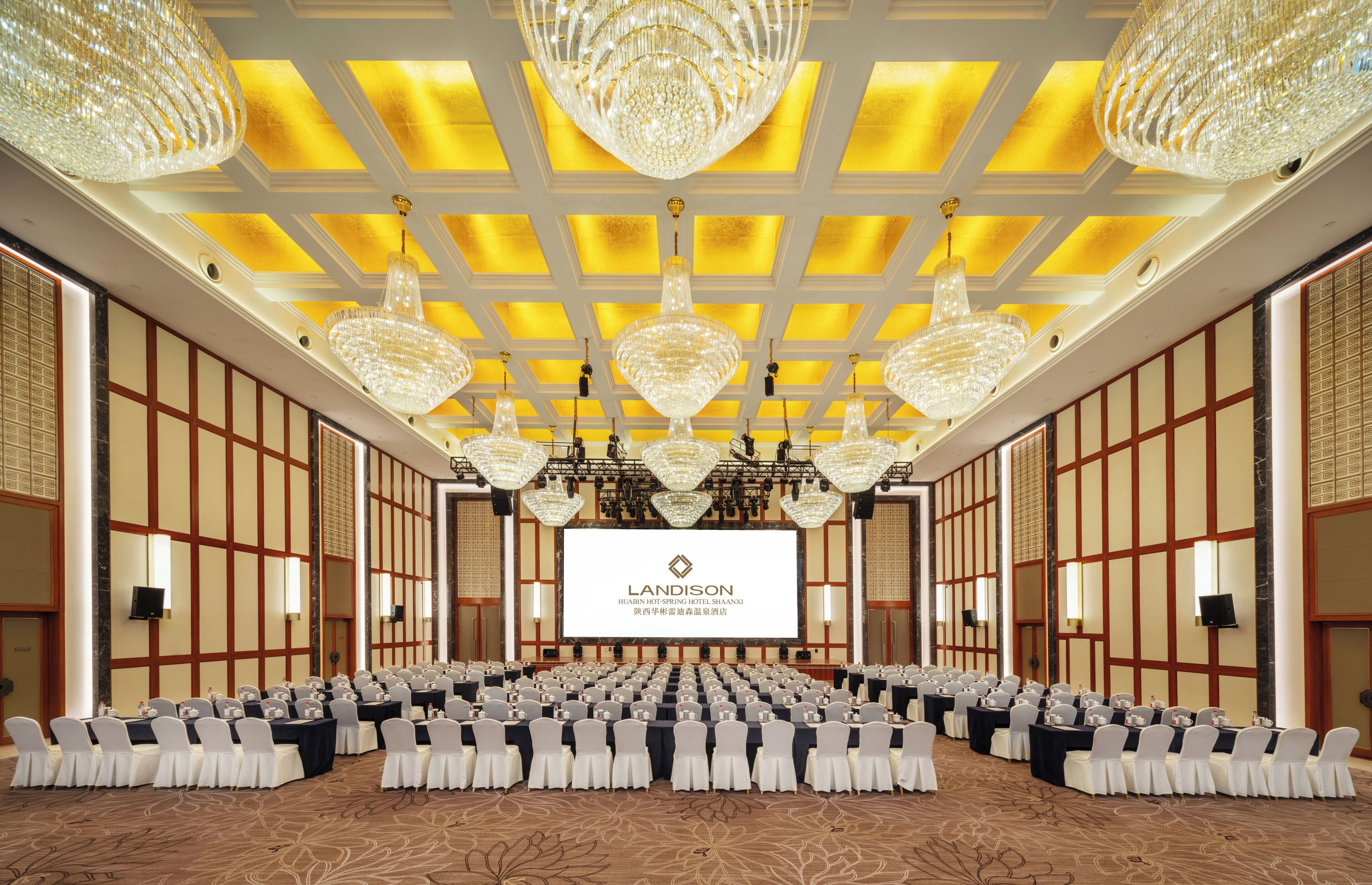 A conference room with multiple tables, chairs, and chandeliers.